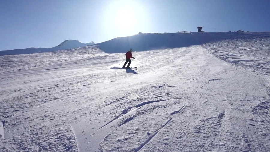 A skier on a sunny snowy slope